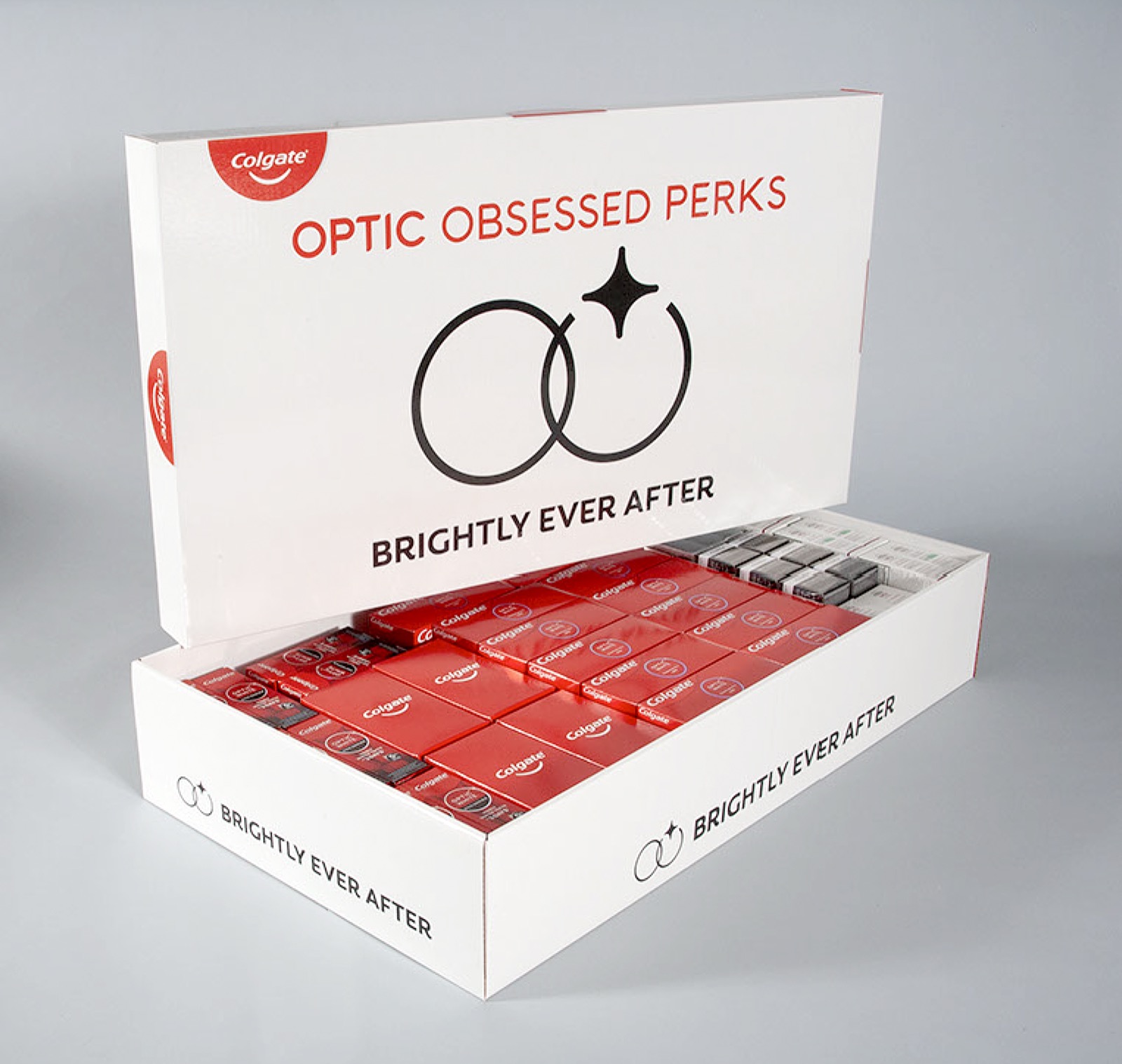 Custom Colgate 'Optic Obsessed Perks — Brightly Ever After' kit produced by HAP: a printed presentation box with its lid raised, packed with rows of Colgate Optic White products