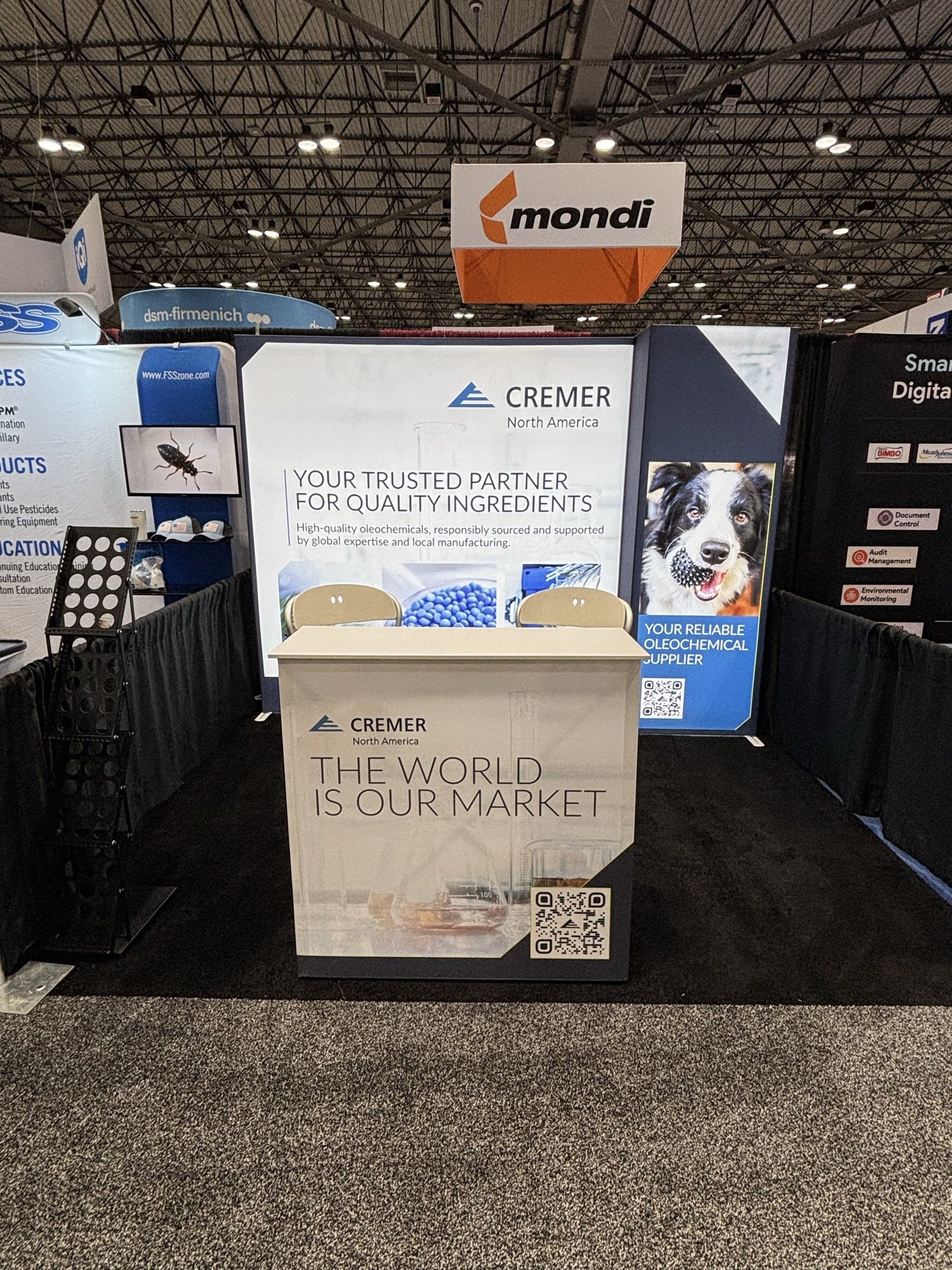 Cremer North America booth with backlit graphic walls and a branded reception counter