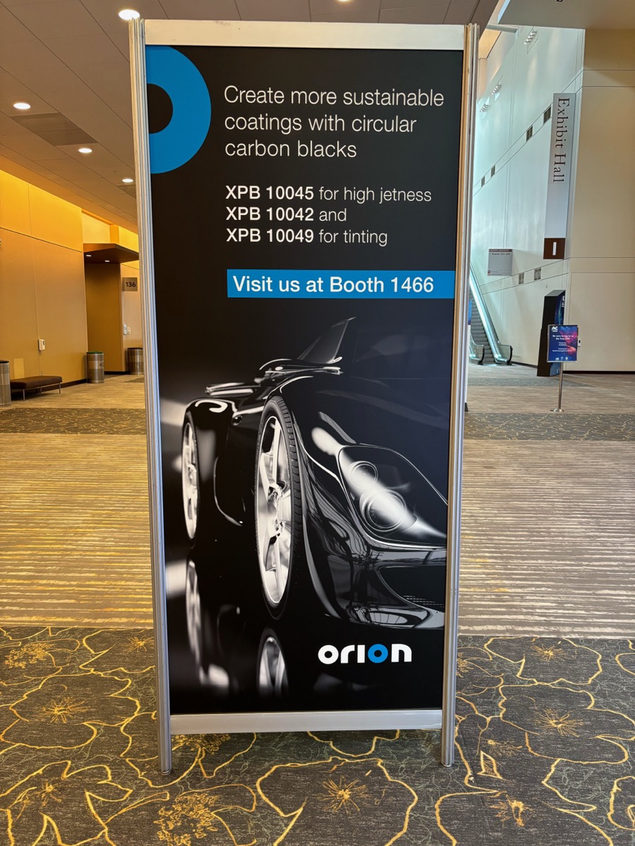 Freestanding Orion banner with a black sports car graphic in a convention center corridor