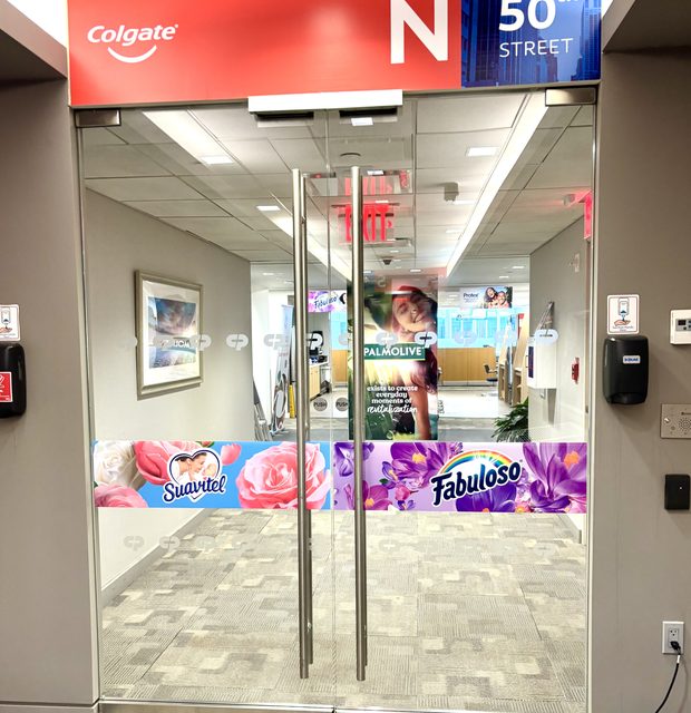 Glass office entrance decorated with Colgate, Suavitel, and Fabuloso brand graphics